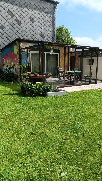 een huis met een patio en een grasveld bij Chez Vladimir in Criquebeuf-en-Caux
