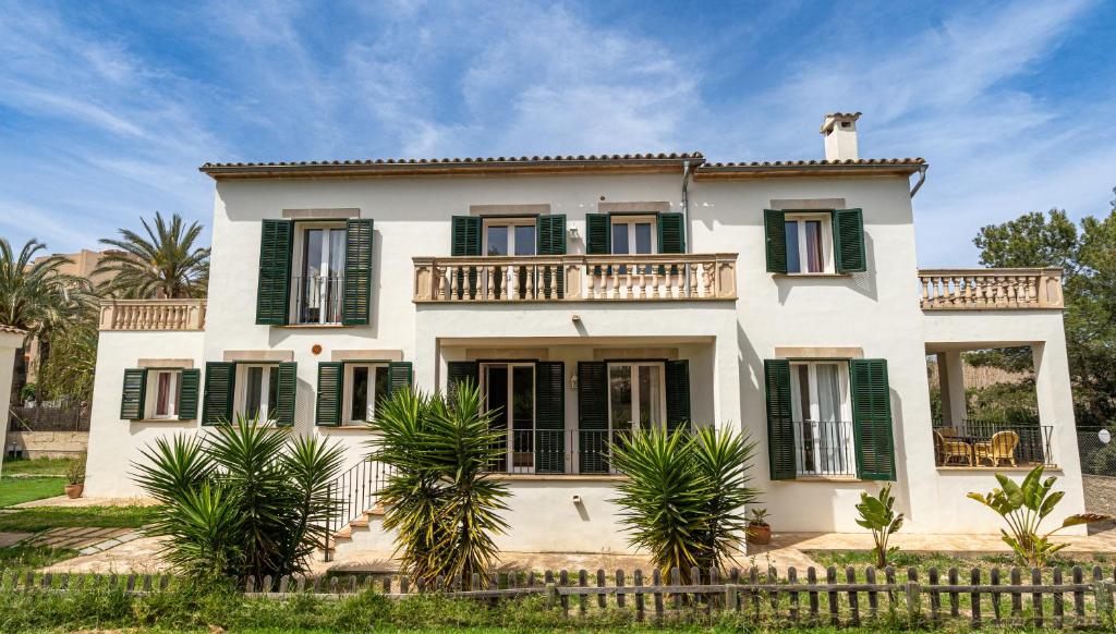 a large white house with green shutters at Houm Villa Samil in Playa de Palma