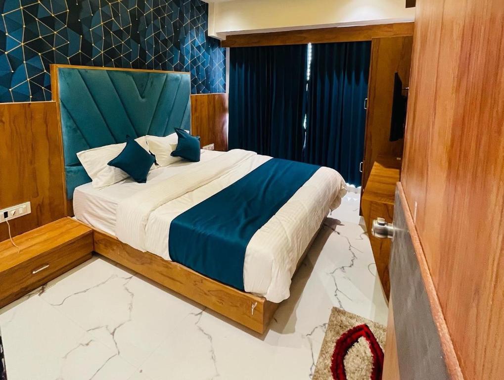 a bedroom with a bed with blue and white sheets at Hotel Paramount Villa in Gandhinagar