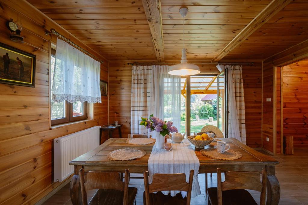 a wooden dining room with a table and chairs at Podlaska chata otoczona ciszą. Na wyłączność in Kleniki