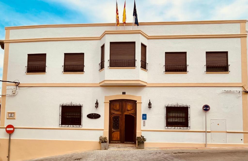 a white building with a brown door at Hotel 3* La Casona de las Flores in Ondara