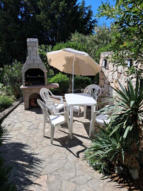 a table and chairs with an umbrella and a fireplace at Apartment Pamela in Gajac