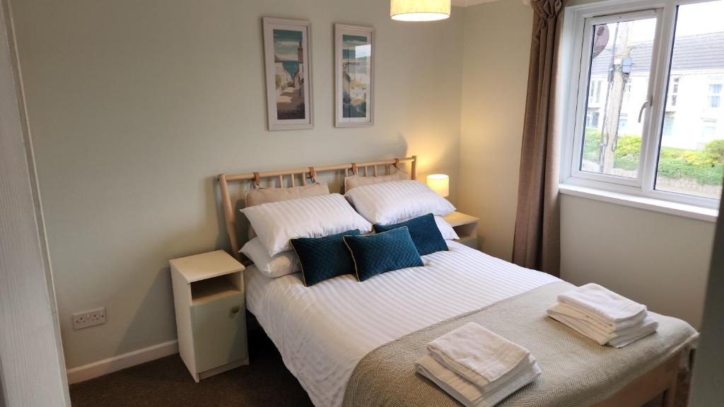 a bedroom with a bed with white sheets and blue pillows at Top Location Perranporth Apartment in Perranporth
