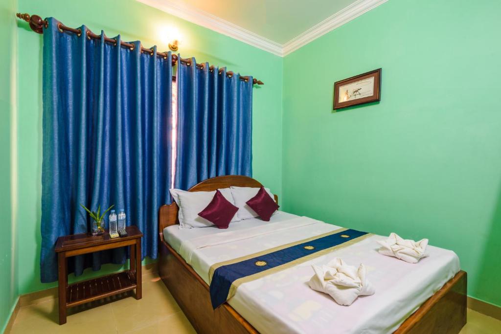 a bedroom with a bed with blue walls and blue curtains at Happy Heng Heang Guesthouse in Siem Reap