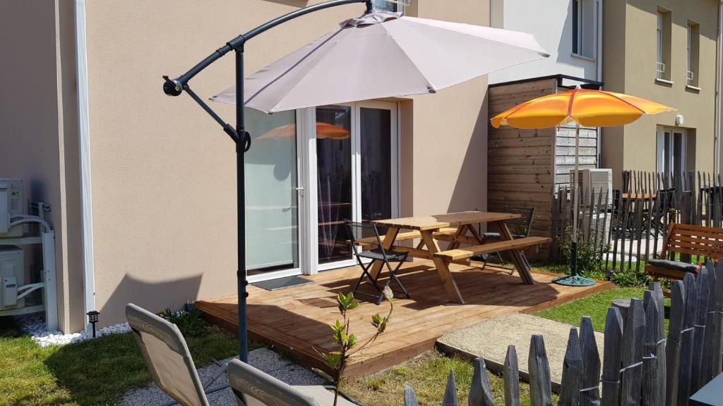 un patio avec une table et un parasol dans l'établissement La cabane de Mimimael Duplex 4 pers proche océan, à Mimizan