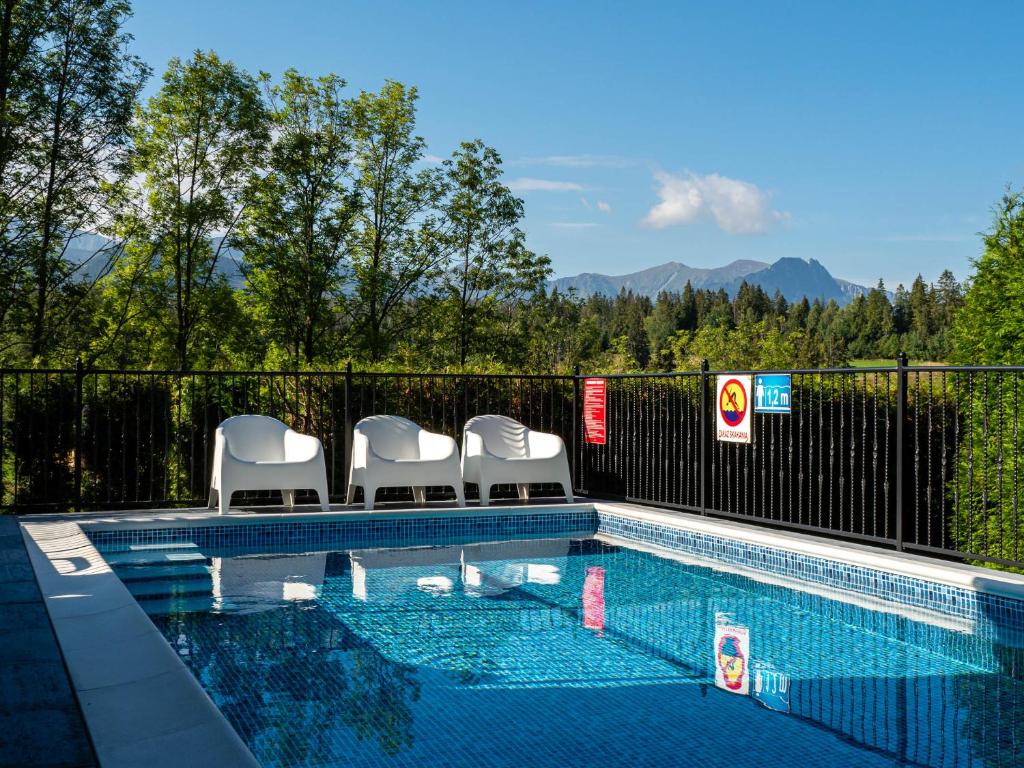 a swimming pool with four white chairs in it at WERONIKA Murzasichle - podgrzewany basen zewnętrzny śniadanie i jacuzzi w cenie in Murzasichle