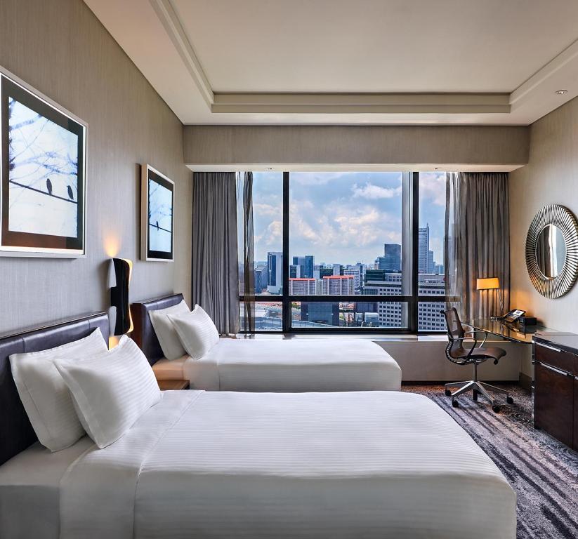 um quarto de hotel com três camas e uma janela em Carlton City Hotel Singapore em Singapura