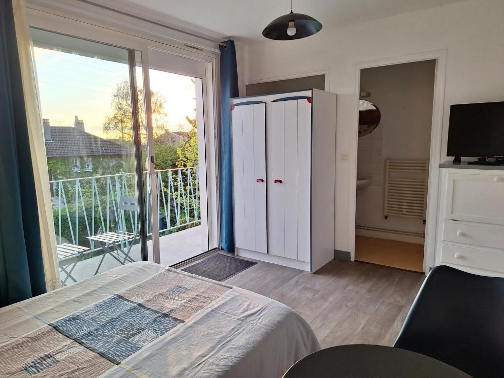 a bedroom with a bed and a balcony with a sliding glass door at le Ferry in Trouville-sur-Mer
