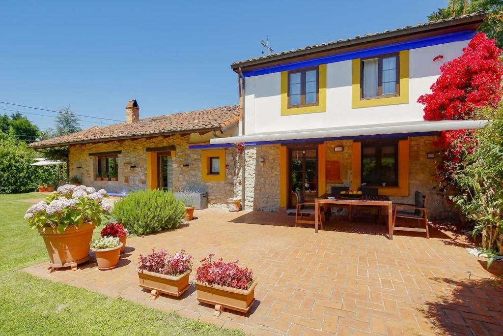 una casa con un patio con flores en macetas en El Gorin Casona en Gijón