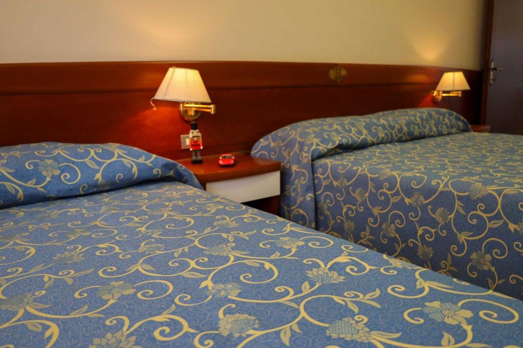 una camera d'albergo con due letti e un tavolo con una lampada di Easy Hotel Meryon a Sottomarina