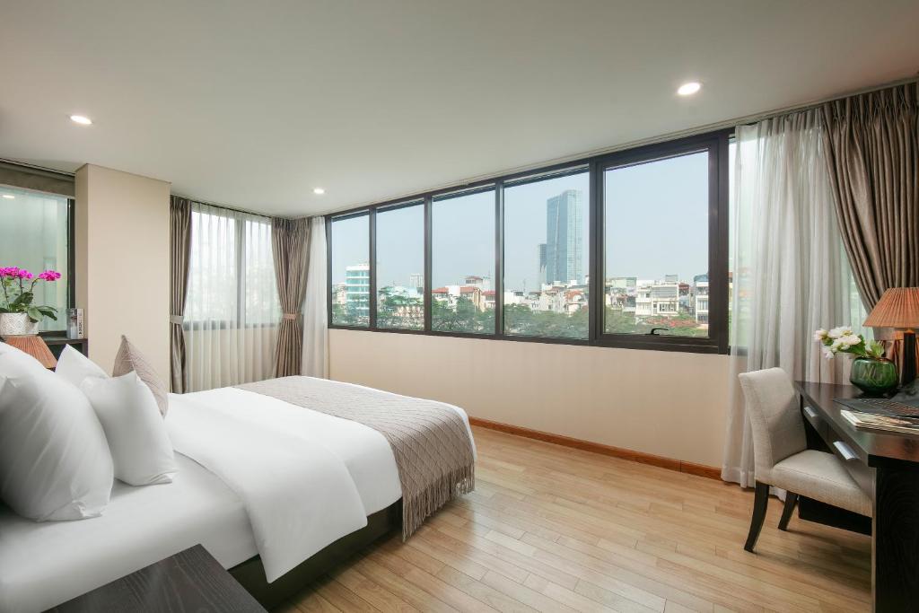 ein Hotelzimmer mit einem Bett, einem Schreibtisch und Fenstern in der Unterkunft HB Serviced Apartment - 121B Quan Hoa in Hanoi