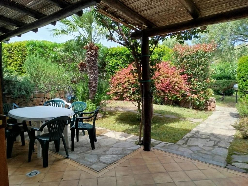 a patio with a table and chairs in a garden at Oasi Boungaville in Porto San Paolo