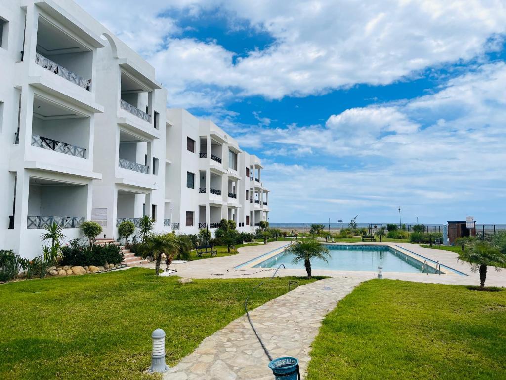 een groot wit appartementencomplex met een zwembad bij Green coastline CHMAALA in Ifargane