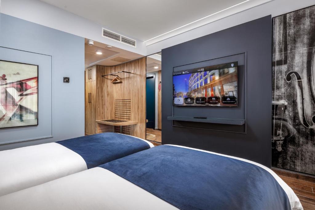 a bedroom with a bed and a flat screen tv at Vivaldi Hotel in St. Julianʼs