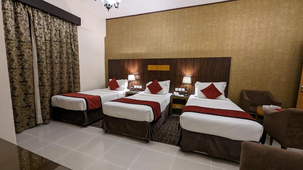 a hotel room with three beds and a desk at City Tower Hotel in Fujairah