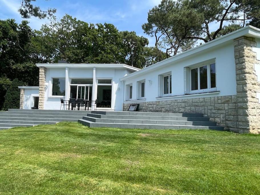 une maison blanche avec une pelouse devant dans l'établissement Briseis, maison d'architecte proche de la mer, à Sainte-Marguerite