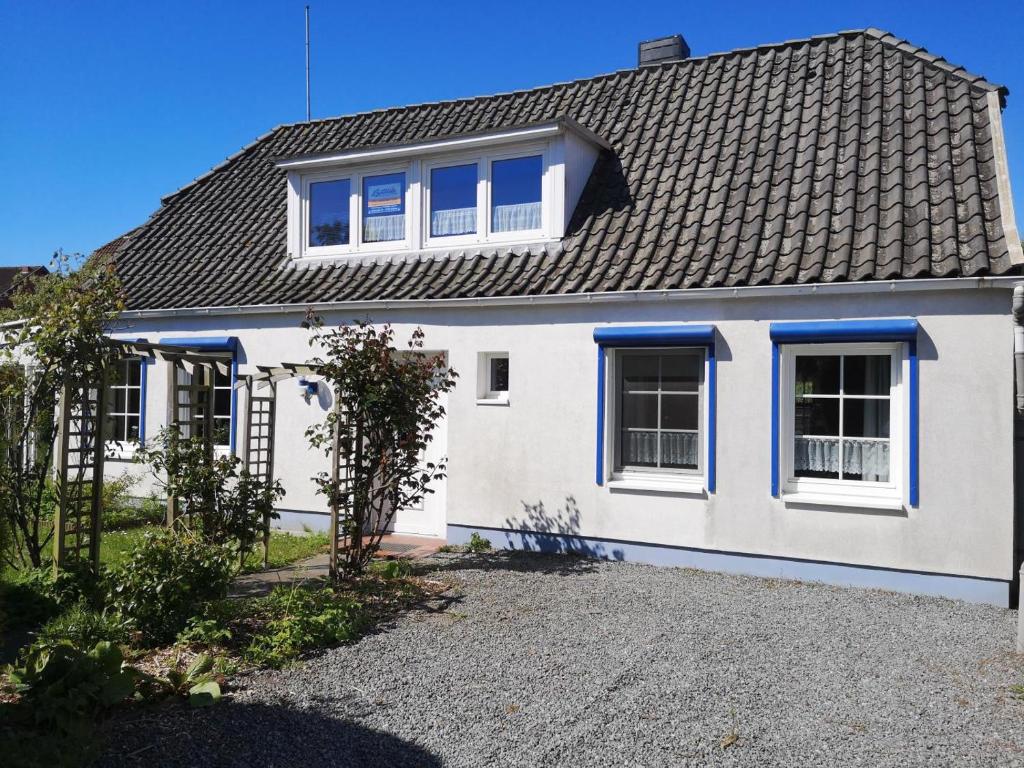 a white house with blue windows and a roof at Memelstrasse 6 in Dahme