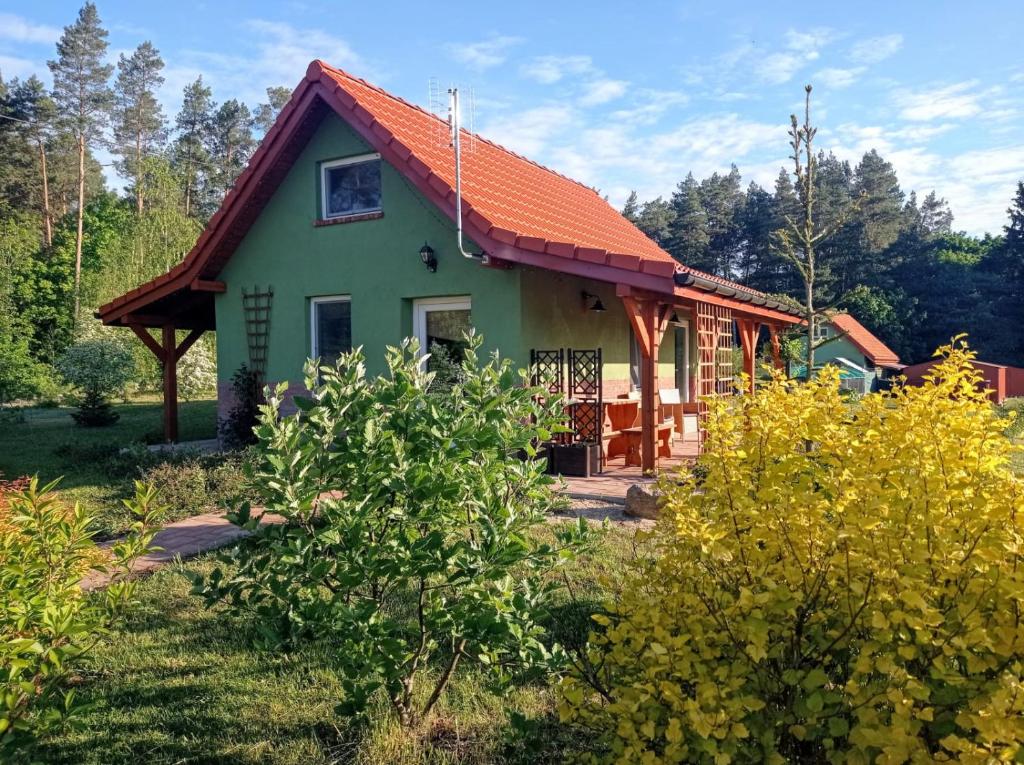 ein kleines grünes Haus mit orangefarbenem Dach in der Unterkunft Zielona Chatka pod Srebrnym Żurawiem in Wydminy