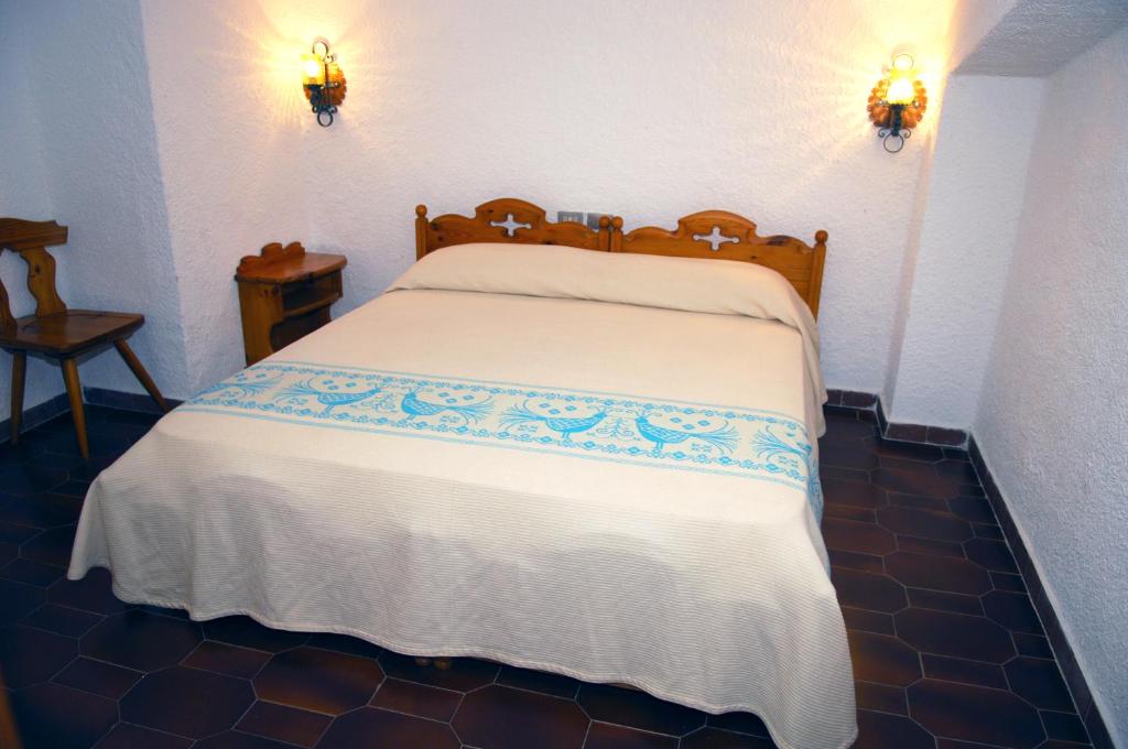 a bed in a bedroom with two lights on the wall at HOTEL al FARO ,SPIAGGIA LA CINTA ,SAN TEODORO in San Teodoro