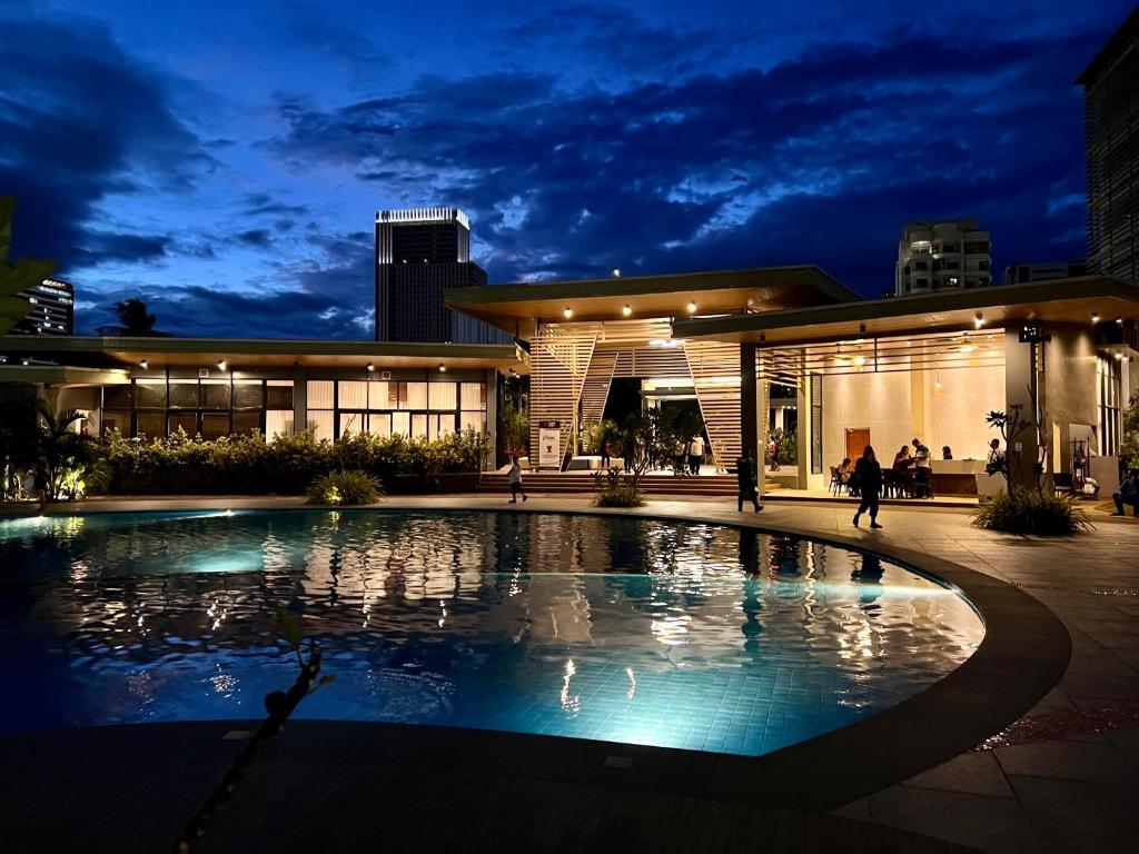- une grande piscine en face d'un bâtiment la nuit dans l'établissement Grand stay at Isla Stays, à Cebu