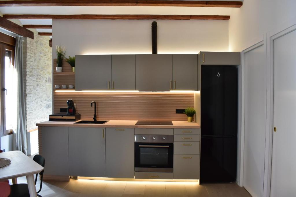 a kitchen with gray cabinets and a black refrigerator at Apartments & Boutique Meraki in Ontinyent