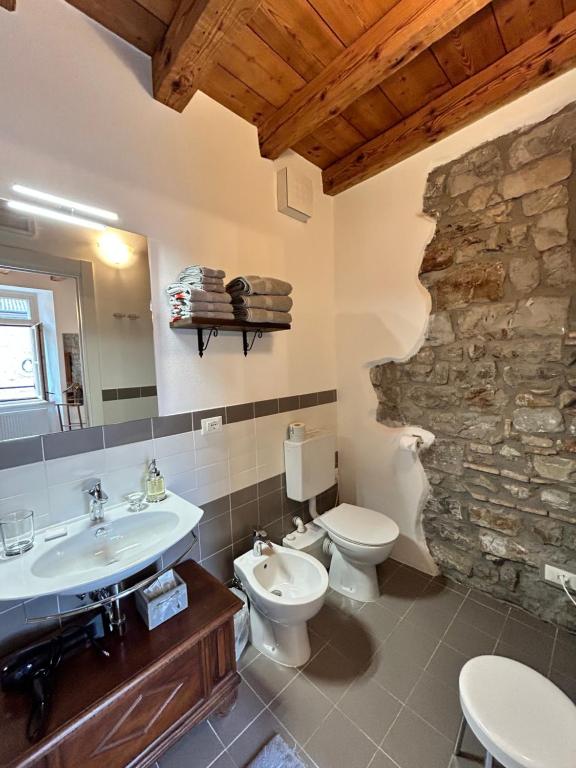 een badkamer met een wastafel, een toilet en een stenen muur bij B&B Domus iulii in Cividale del Friuli