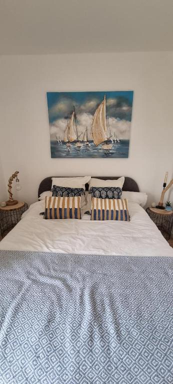 a bedroom with a large white bed with a painting of ships at Chambre St-Loup in Saint-Mathieu-de-Tréviers