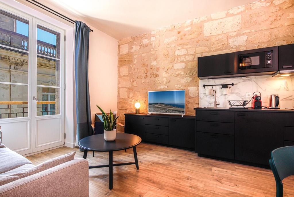 salon z kanapą i laptopem na ścianie w obiekcie Appartements - Bordeaux Centre Gare w mieście Bordeaux