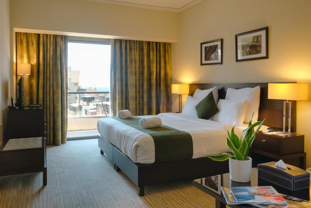een hotelkamer met een bed en een groot raam bij The Parisian Hotel in Beiroet