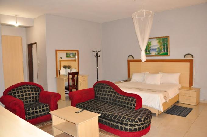 ein Hotelzimmer mit einem Bett und zwei Stühlen in der Unterkunft CROWN HOTEL INTERNATIONAL in Lilongwe