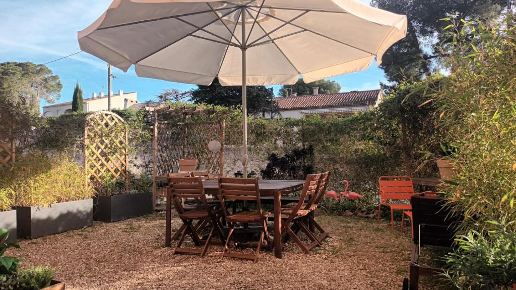 - une table et des chaises avec un parasol dans le jardin dans l'établissement Plage à proximité jardin arboré tout à pied tout confort, à Saint-Elme