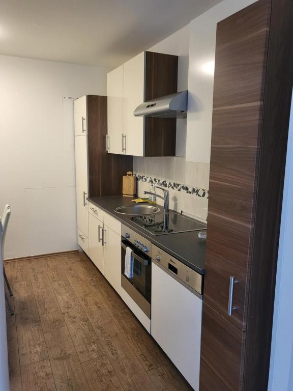 una cocina con armarios blancos y fregadero en Monteur Apartments, en Fohnsdorf