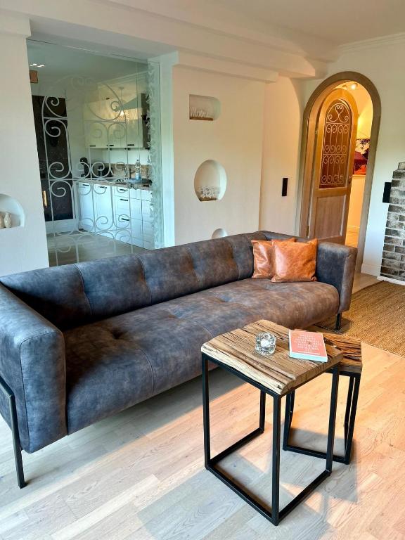 a brown leather couch in a living room with a table at Residenz am Pferdemarkt - exklusives Wohnen im Herzen Ostfrieslands - stillvoll & luxuriös in Aurich
