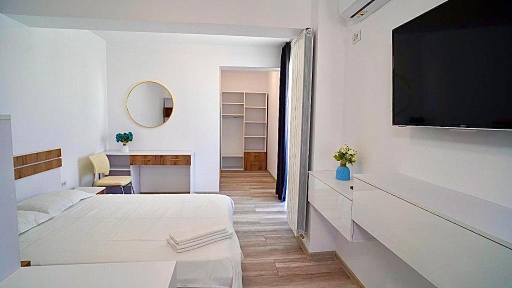 Dieses weiße Zimmer verfügt über ein Bett und einen Flachbild-TV. in der Unterkunft Mamaia-Nord Boutique Apartments in Mamaia Nord – Năvodari