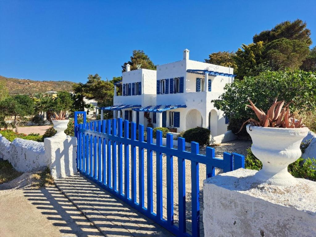 a blue fence in front of a white house at Iremia North Kokkali Beach Leros in Gourna