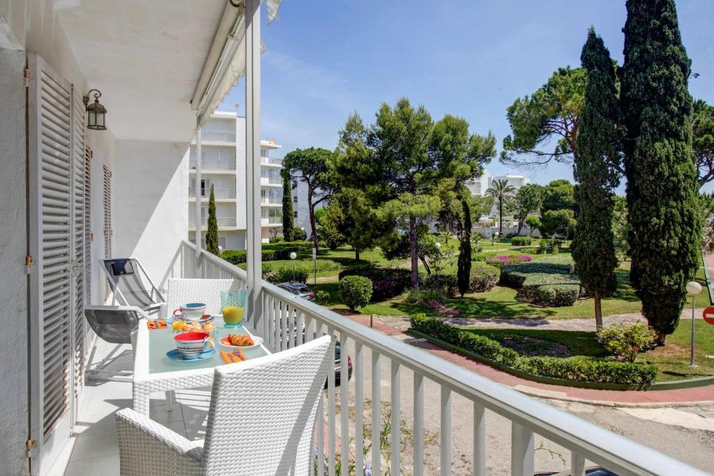 un balcón con sillas blancas y una mesa con comida. en Complejo Ducal Center de playa gandia en Playa de Gandia