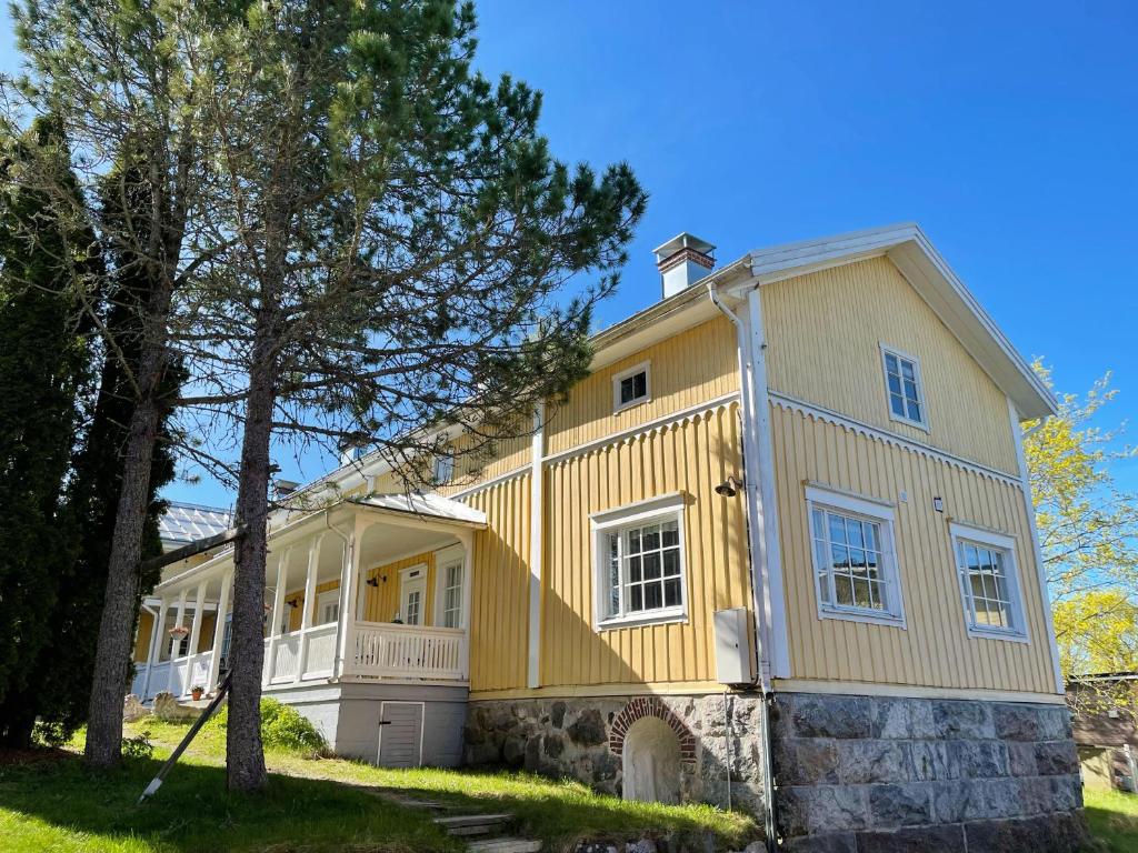 Sauvo的住宿－Vinter Bed & Breakfast，前面有一棵树的黄色房子