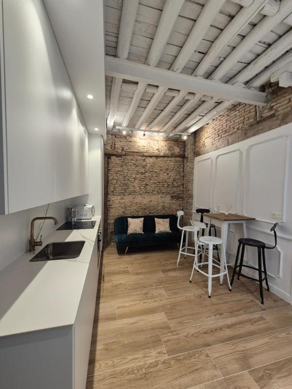 a kitchen with white cabinets and a brick wall at Hermosos Apartamentos en pleno Centro in Granada