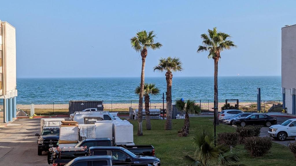 a parking lot with palm trees and a beach at Waterfront North Beach Condo with beach and pool access in Corpus Christi