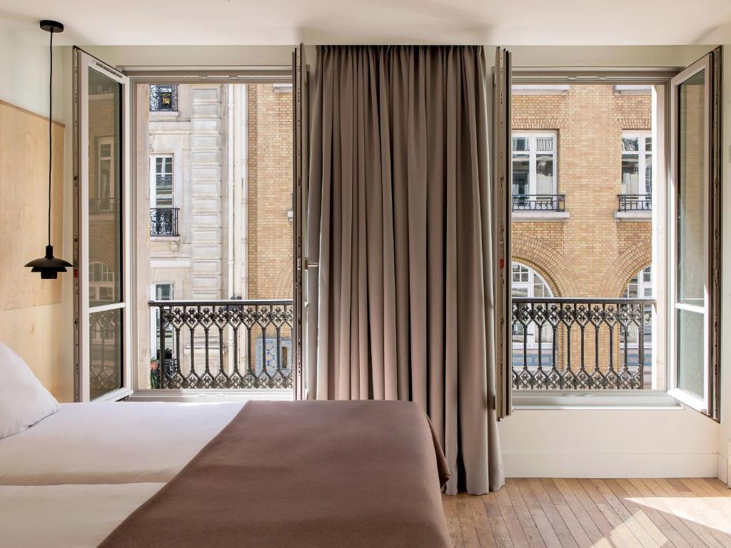 New Hotel Opéra في باريس: غرفة نوم بسرير ونافذة كبيرة