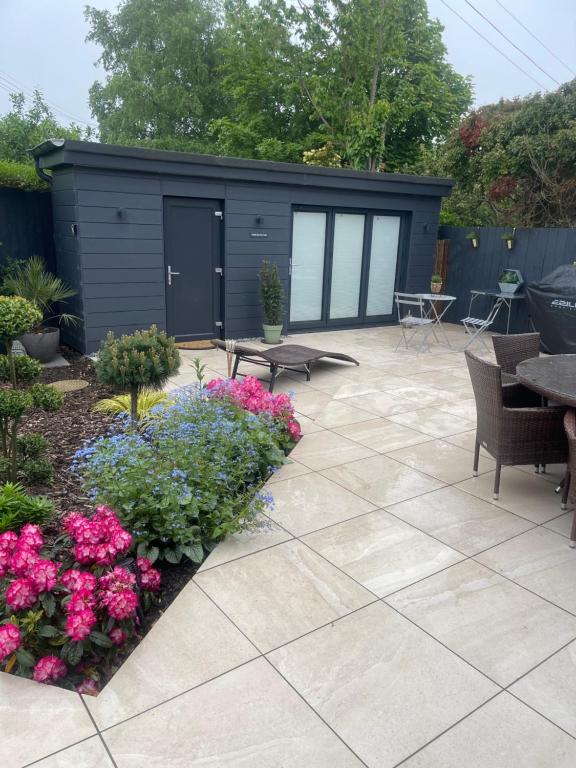 a patio with flowers and a black shed at Cabin by the coast in Edinburgh