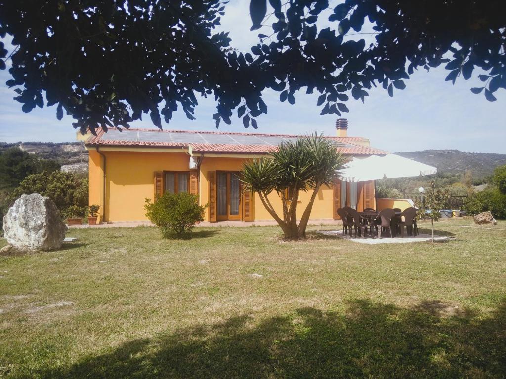 żółty dom ze stołem i krzesłami na dziedzińcu w obiekcie Grotta Delle Fate w mieście Ossi