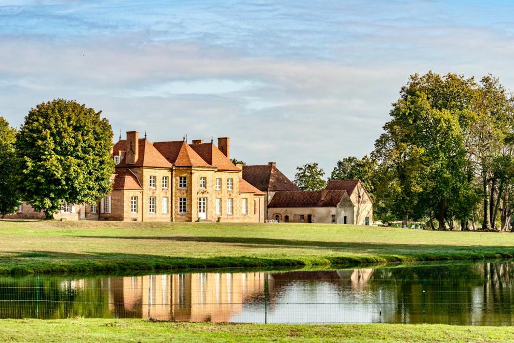 stary dom ze stawem przed nim w obiekcie Les Louteaux - Splendide Château du XVIII -Piscine- Parc de Lamas w mieście Chézy