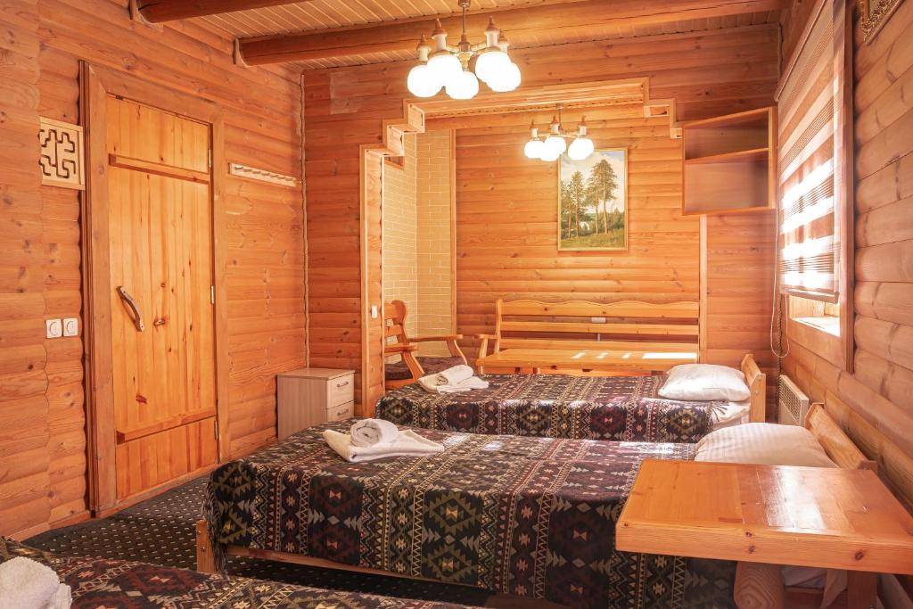 1 dormitorio con 2 camas en una cabaña de madera en BOROVOE Country Club, en Burabay