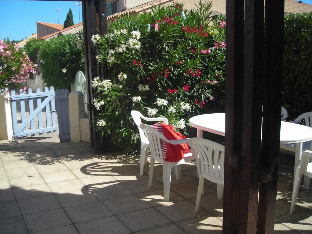 - une terrasse avec une table, des chaises et des fleurs dans l'établissement maison dans résidence piscine tennis, à Vic-la-Gardiole
