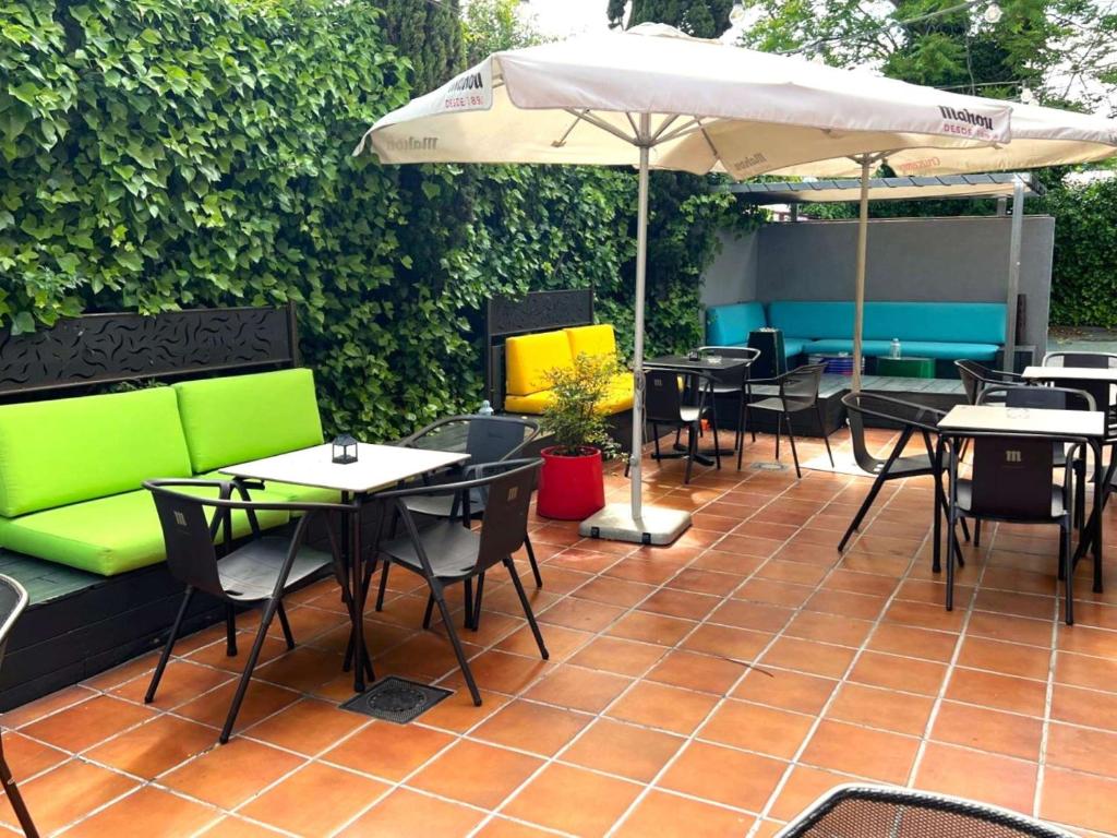 patio ze stołami, krzesłami i parasolem w obiekcie Ibis Madrid Fuenlabrada w mieście Fuenlabrada