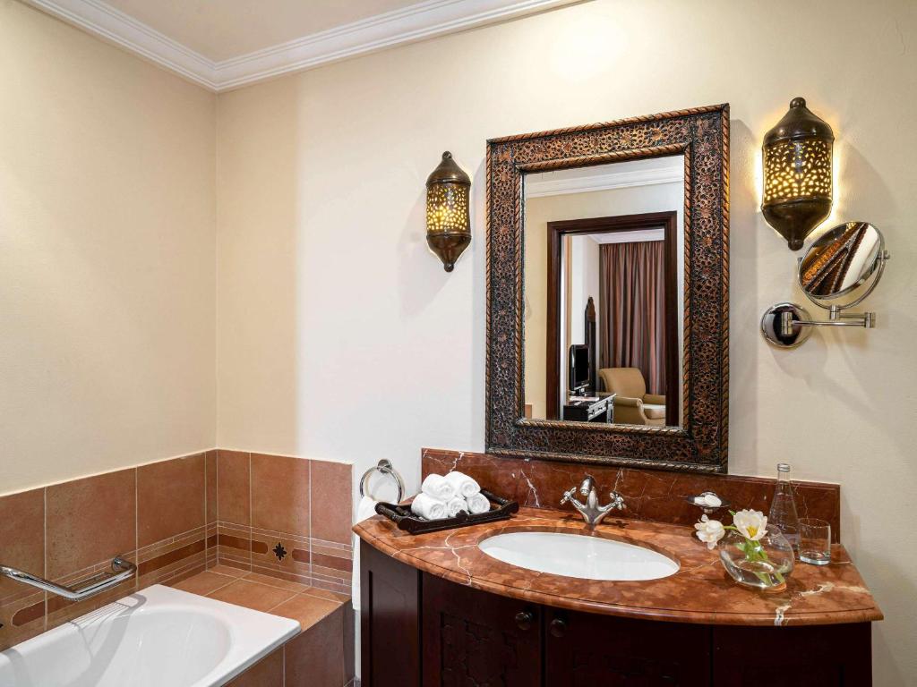 Mercure Grand Hotel Seef - All Suites في المنامة: حمام مع حوض ومرآة
