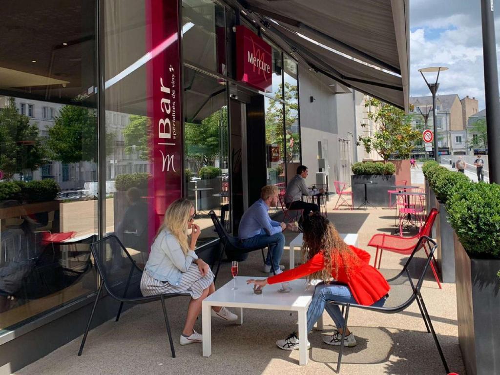 a group of people sitting in chairs outside a store at Mercure Cholet Centre in Cholet