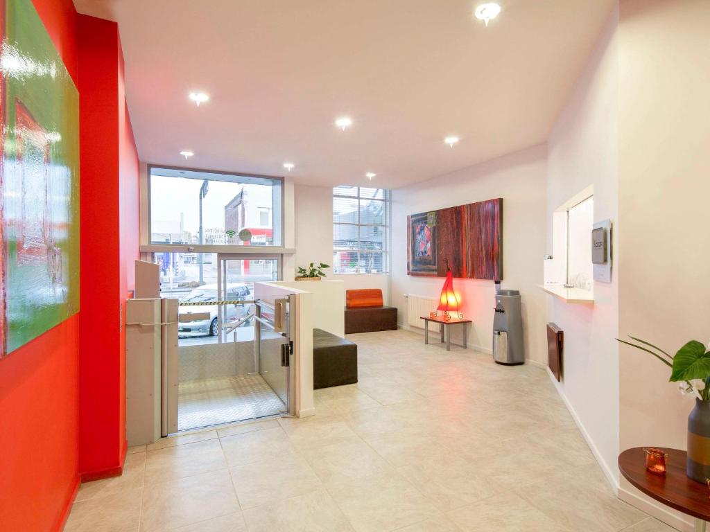 un salon avec un mur rouge et un salon dans l'établissement Ibis Styles Invercargill, à Invercargill