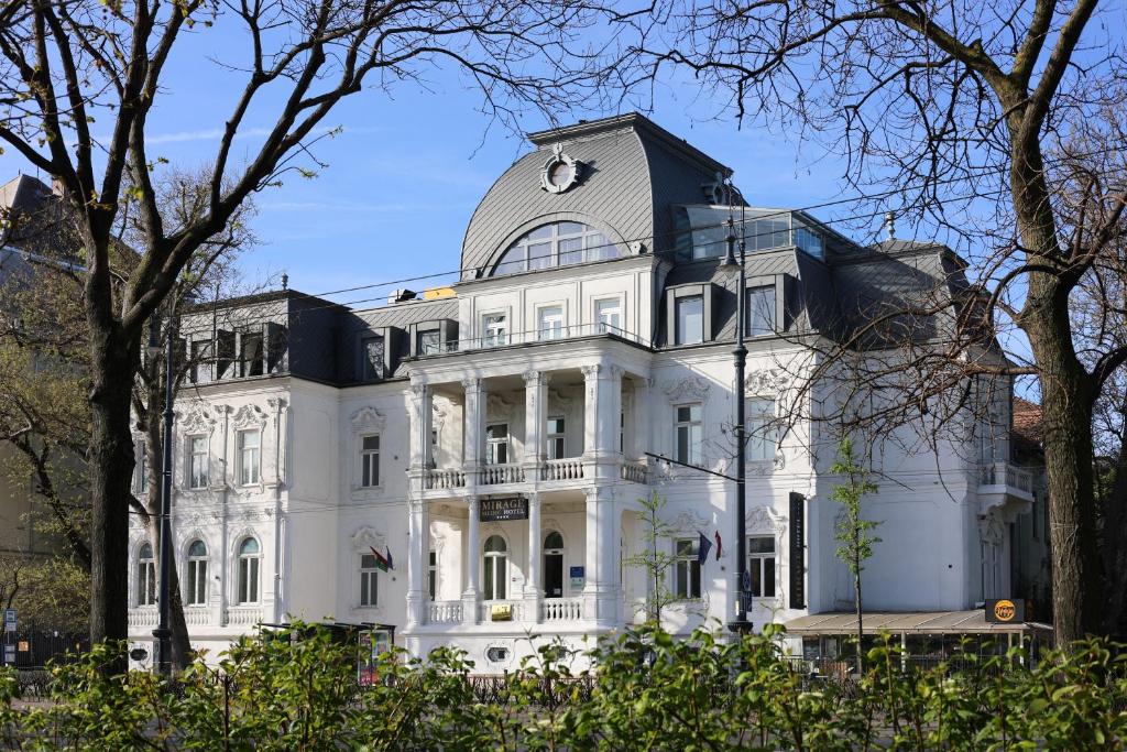 a white mansion with a clock on the top of it at Mirage Medic Hotel in Budapest